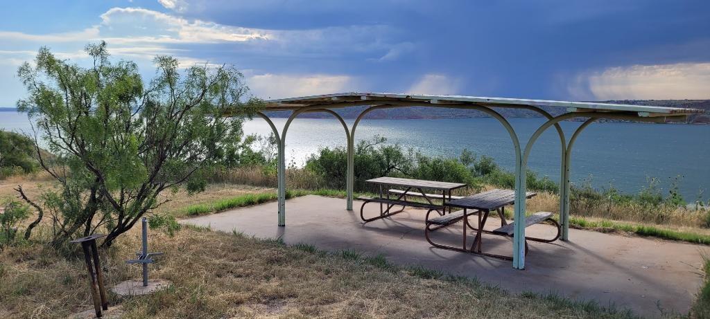 Picnic shelter at a campsite overlooking Lake Meredith. The sky is blue with no clouds.