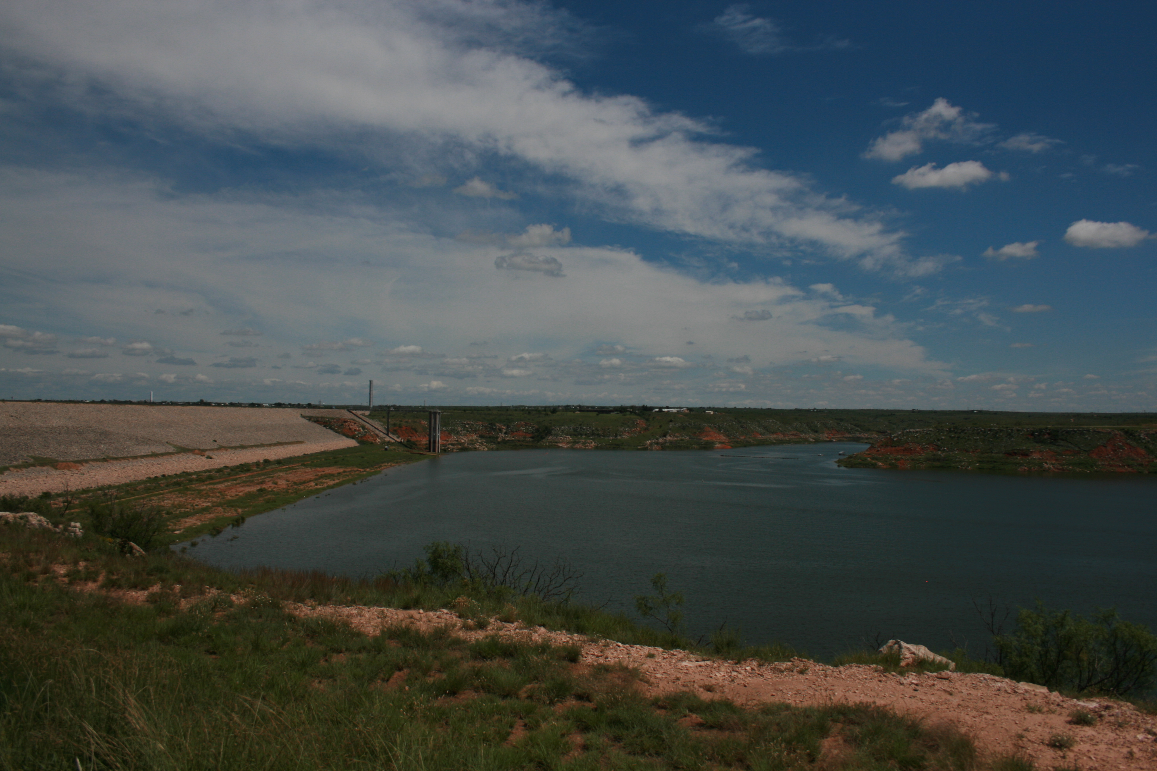 Sanford Dam and Lake Meredith. The lake is deep blue with white clouds above in the sky.