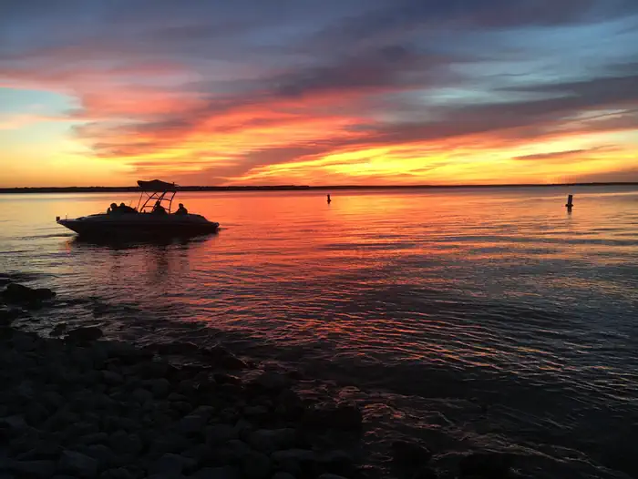 Wake boat silhouetted by sunset from beach at McCown Day Use Park