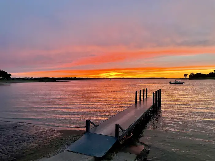 Sunset silhouetting two boats with boat ramp and courtesy dock in the foreground