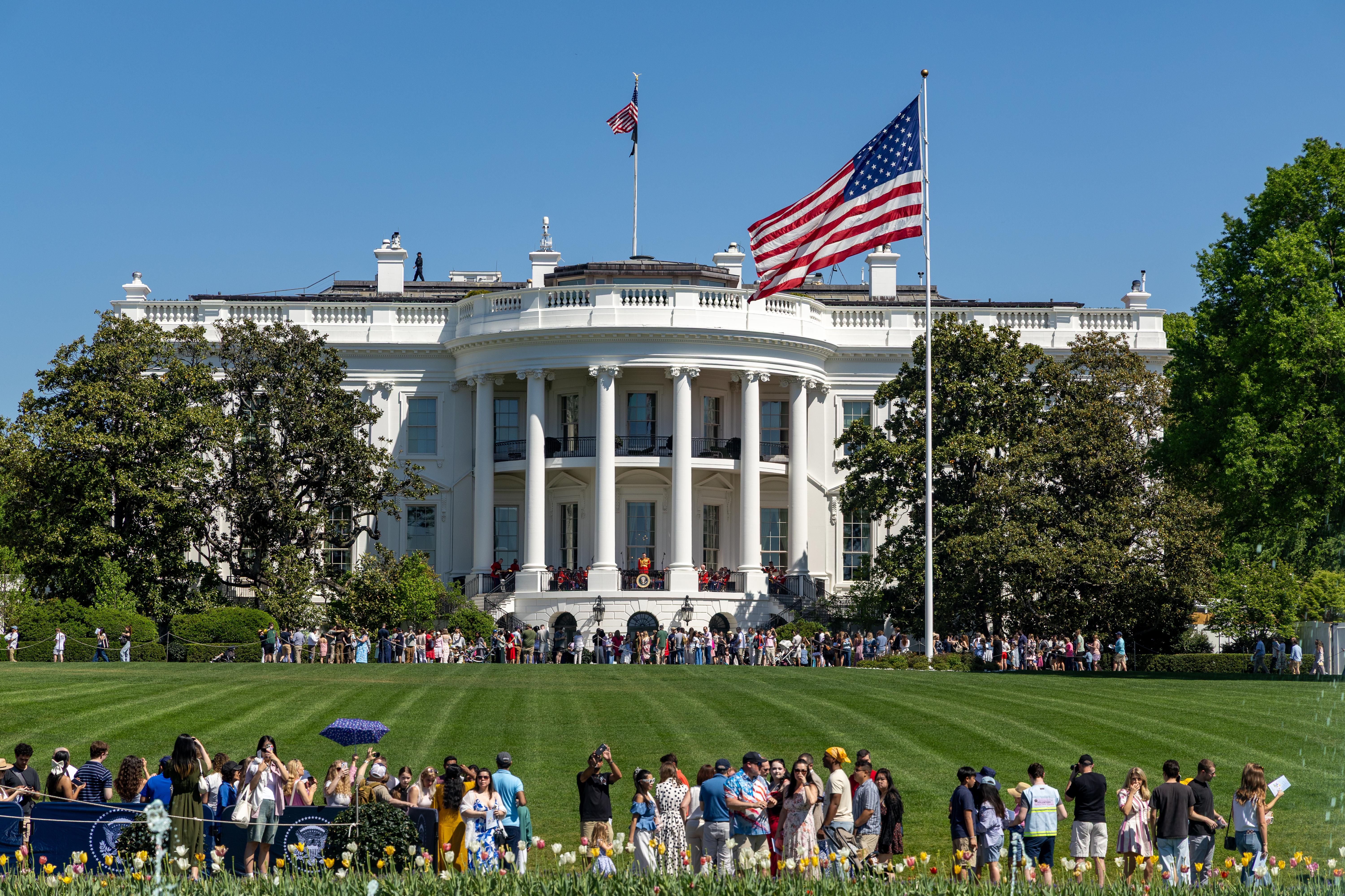 Crowds of people populate the White House South Lawn on a sunny day with the White House in view